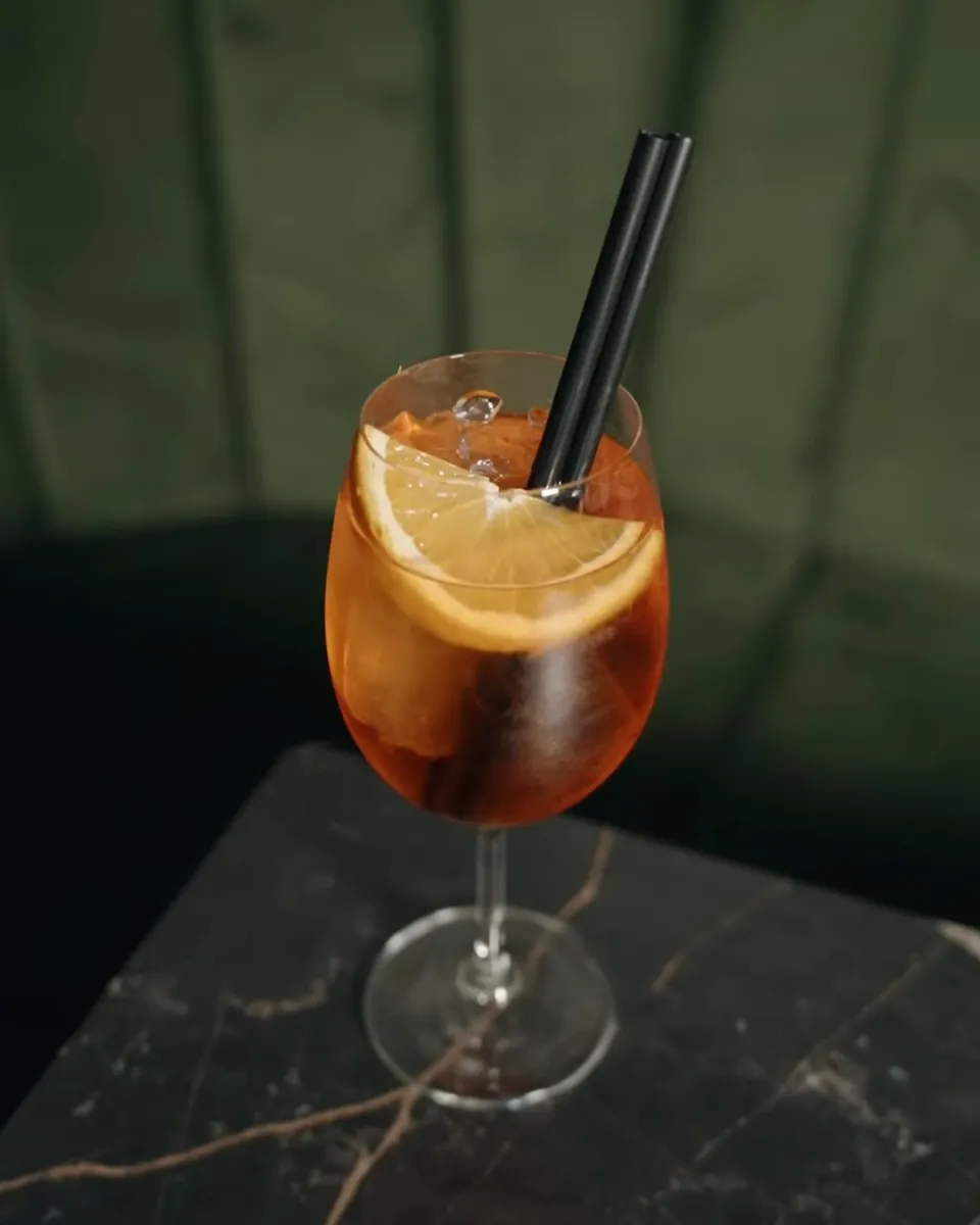 Aperol Spritz sa kriškom narandže na tamnom stolu