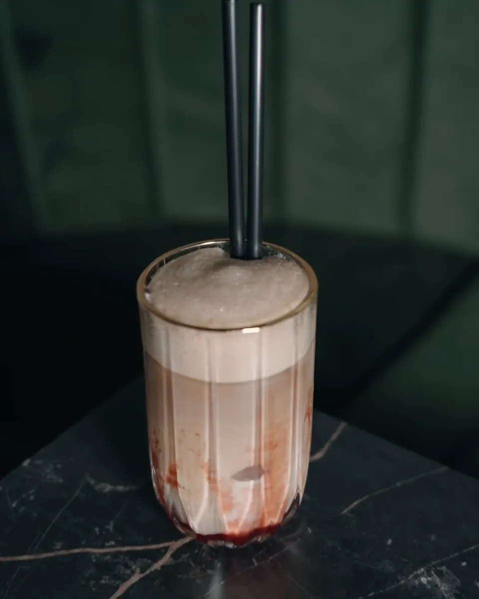 Ice coffee sa jagodom u visokoj čaši na tamnom stolu