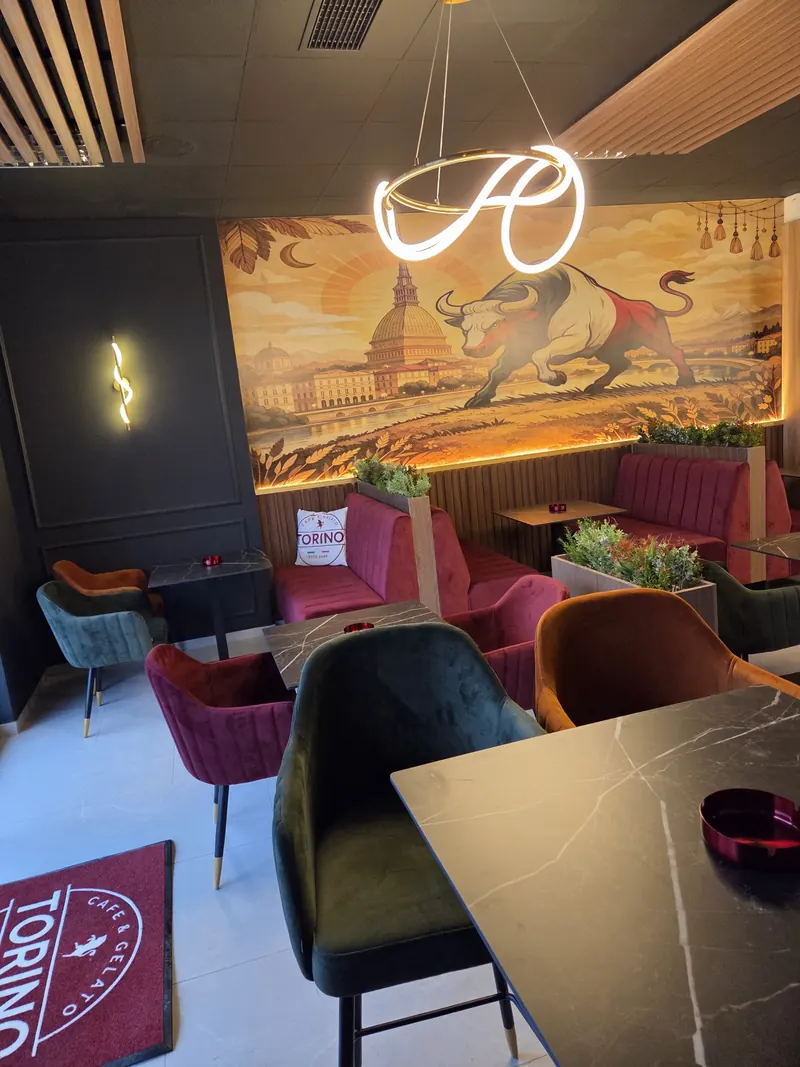Enterijer kafića TORINO sa muralom bika, neonskom svjetiljkom i foteljama od somota